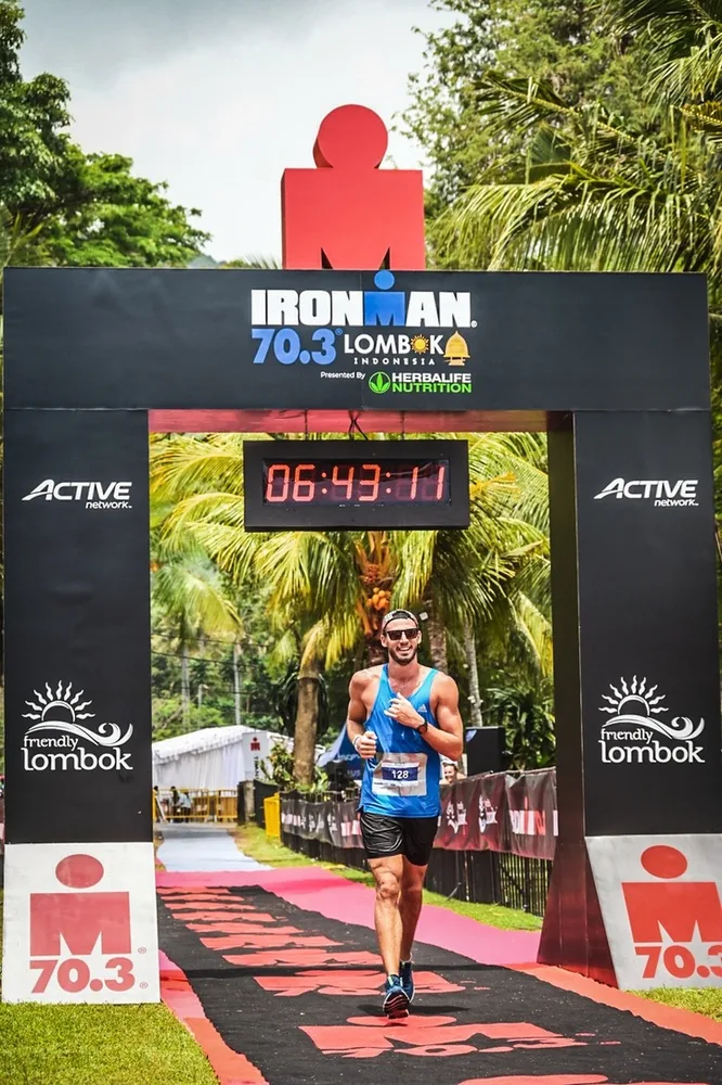 Lewis crossing the finish line of an Ironman 70.3